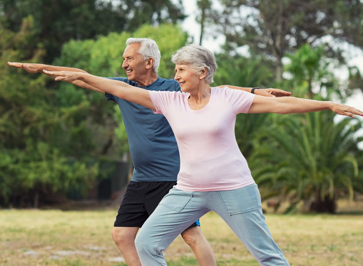 active seniors exercising, doing yoga outdoors