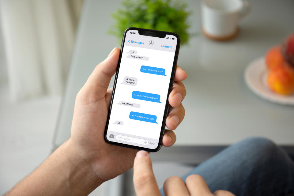 man hand holding phone with app messenger on the screen in room of the house