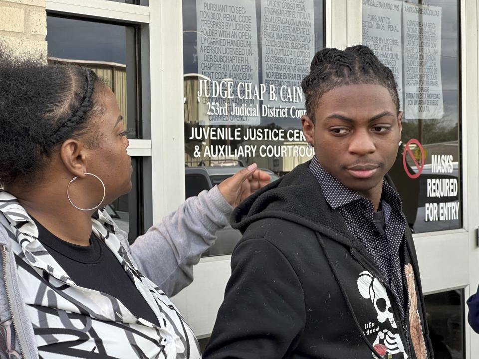 Darryl George, an 18-year-old high school junior, and his mother, Darresha George, stand outside a courthouse in Anahuac, Texas, on Wednesday, Jan. 24, 2024. A judge ordered Wednesday that a trial be held next month to determine whether George can continue being punished by his district for refusing to change a hairstyle he and his family say is protected by a new state law. (AP Photo/Juan A. Lozano)