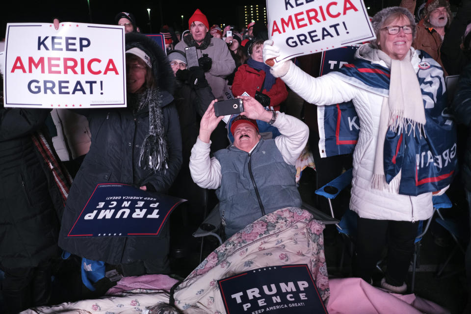 People watch President Donald Trump speak on a large television outside of a rally in Wildwood, N.J., Tuesday, Jan. 28, 2020. (AP Photo/Seth Wenig)