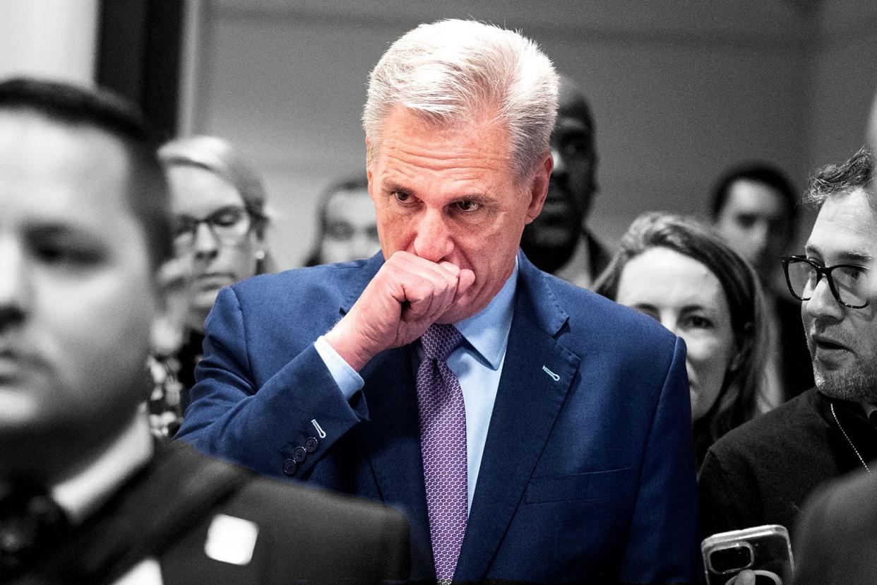 Kevin McCarthy surrounded by reporters with his fist over his mouth.