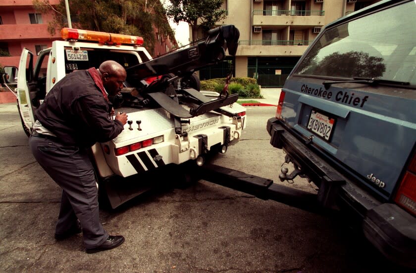 ME.Tow1.0312.CC...Carlton Johnson, who has been with Wilshire Towing Co. for the past 7 years, picks up a car to be towed in for parking violations. Johnson has been in the towing business for 16 years.Photo/Art by:Carolyn Cole