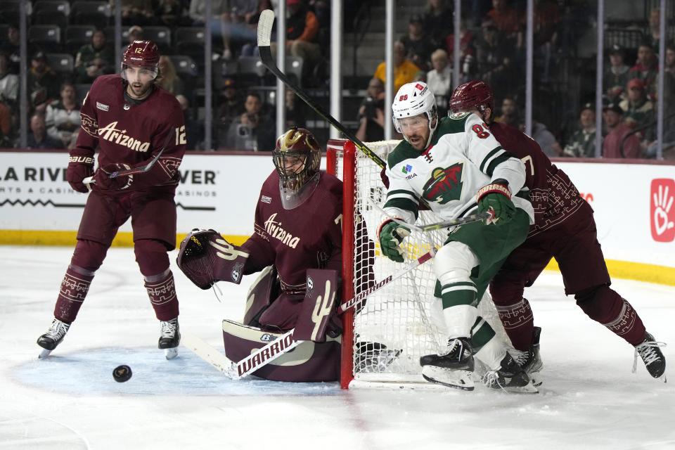 Minnesota Wild center Frederick Gaudreau (89) skates after the puck in front of Arizona Coyotes defenseman Connor Mackey (12), defenseman Victor Soderstrom (77), and goaltender Karel Vejmelka (70) during the third period of an NHL hockey game, Sunday, March 12, 2023, in Tempe, Ariz. Arizona won 5-4 in overtime. (AP Photo/Rick Scuteri)