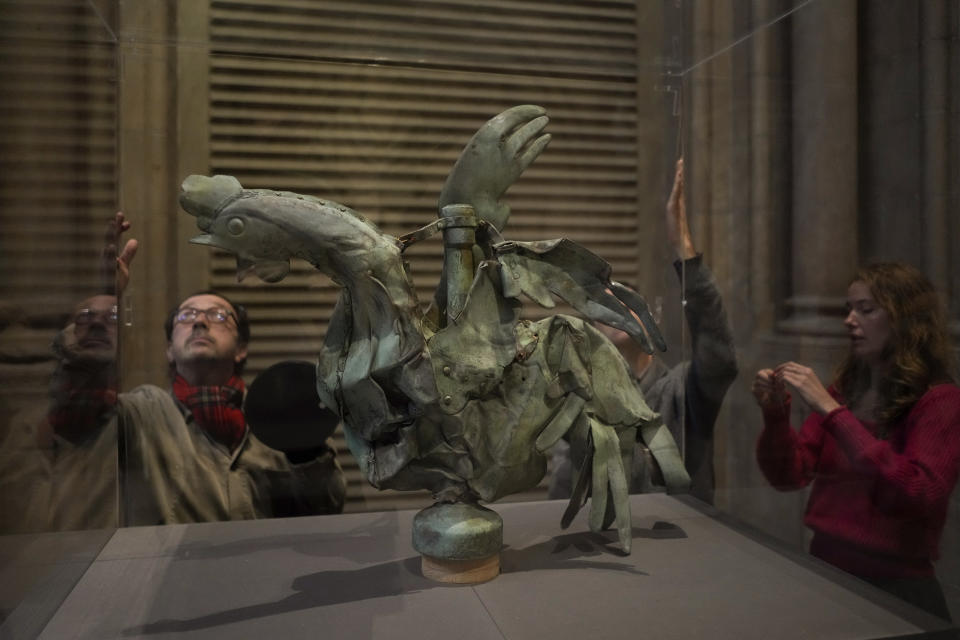 Curator in charge of the Galerie des moulages at the Cité de l'architecture et du patrimoine, Isabelle Marquette, right, and technicians place a glass panel around the rooster which sat atop of the spire of the Notre-Dame cathedral, in Paris, Friday, Dec. 15, 2023. Roosters are a symbol of France. The small bird that adorned Notre Dame plunged to the ground in the April 2019 fire that collapsed the spire and consumed the roof. (AP Photo/Thibault Camus)