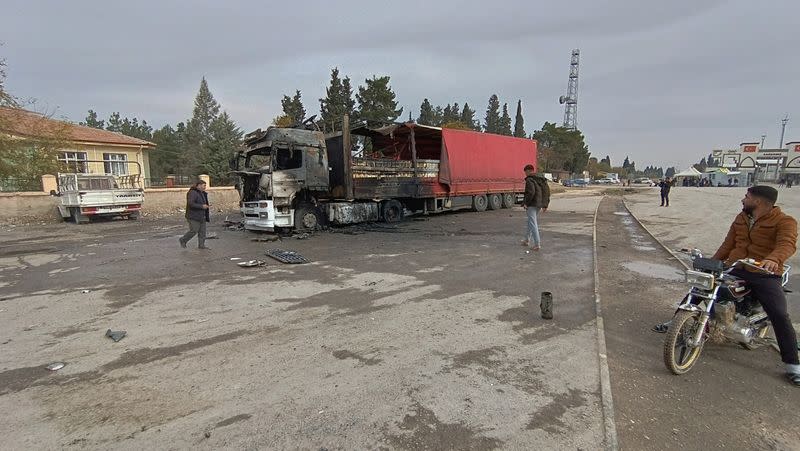 Locals inspect a burned truck hit by one of the rockets fired from northern Syria in the Karkamis district