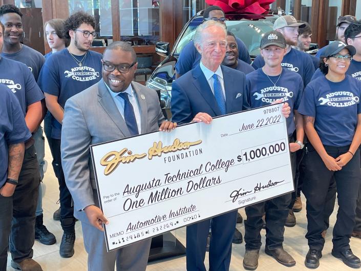 Flanked by students in Augusta Tech's automotive technology program, school President Dr. Jermaine Whirl (left) and Jim Hudson, founder of Jim Hudson Automotive Group, hold an oversized $1 million donation check at Jim Hudson Lexus on Thursday.