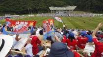 In this Sunday, Aug. 19, 2018, photo, fans watch as rugby players of Kamaishi Seawaves and Yamaha Jubilo play during an opening match at new Kamaishi Recovery Memorial Stadium in Kamaishi, northern Japan. Japan opened a new stadium for the 2019 Rugby World Cup on the site of a school that was destroyed by a devastating tsunami in 2011. About 6,500 fans turned out Sunday for a memorial match in the small coastal city of Kamaishi to honor the victims of the tsunami. (Yusuke Ogata/Kyodo News via AP)