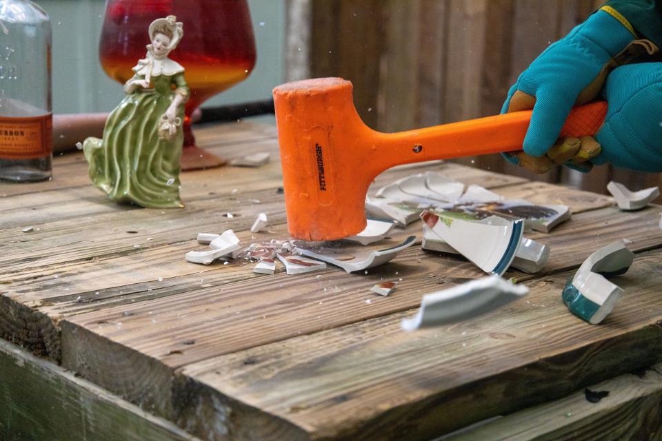 Tiffany Noell smashes a plate with an orange mallet at Smithereens' new permanent location on Friday, Aug. 19. Many of the objects are made of glass, and are broken with mallets, hammers and baseball bats.