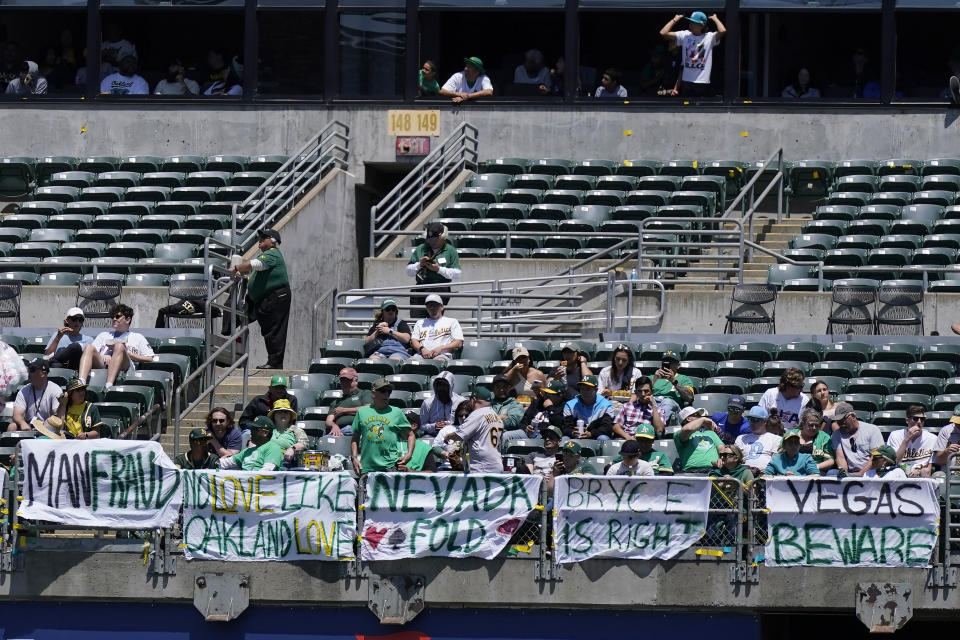 Fans sit behind signs hanging in right field at RingCentral Coliseum protesting the Oakland Athletics' proposed move to Las Vegas during the fifth inning of a baseball game between the Athletics and the Philadelphia Phillies in Oakland, Calif., Saturday, June 17, 2023. (AP Photo/Jeff Chiu)