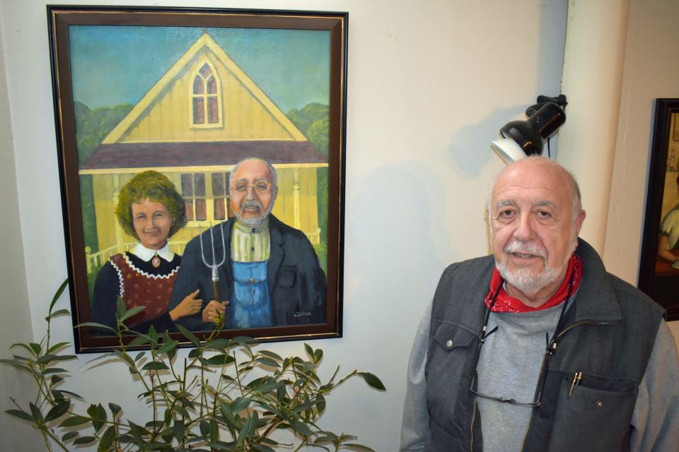 Joe Geha poses by his painting inspired by Grant Wood's "American Gothic," where he and his wife Fern Kupfer are depicted instead of the original pair.