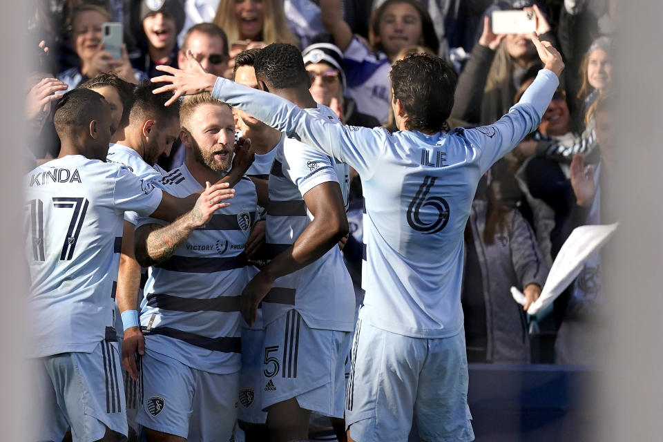 Sporting Kansas City forward Johnny Russell, center, celebrates with teammates after scoring a goal during the first half of an MLS soccer match against Real Salt Lake Sunday, Nov. 28, 2021, in Kansas City, Kan. (AP Photo/Charlie Riedel)