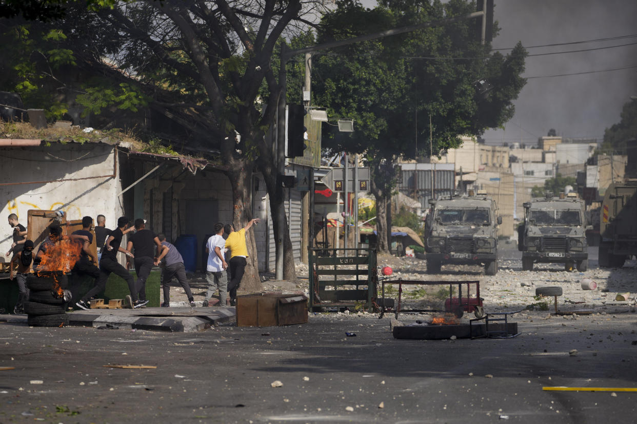 Palestinian demonstrators clash with the Israeli army while forces carry out an operation in the West Bank town of Nablus, Tuesday, Aug. 9, 2022. Israeli police said forces encircled the home of Ibrahim al-Nabulsi, who they say was wanted for a string of shootings in the West Bank earlier this year. They said al-Nabulsi and another Palestinian militant were killed in a shootout at the scene, and that troops found arms and explosives in his home. (AP Photo/Majdi Mohammed)