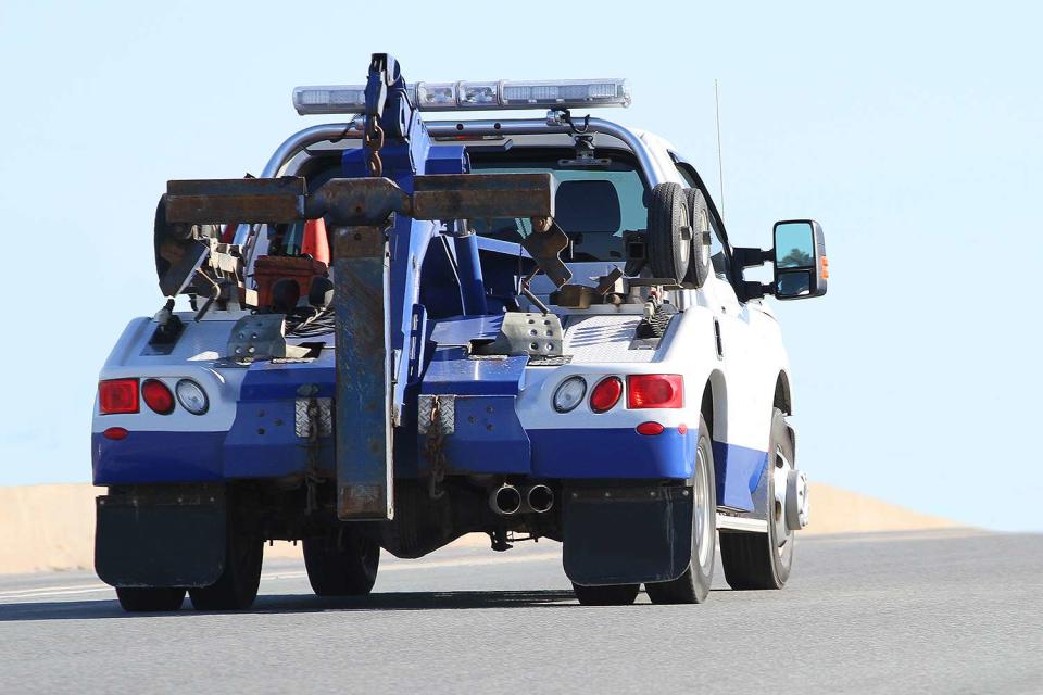 Rear view of a nondescript tow truck traveling on a highway