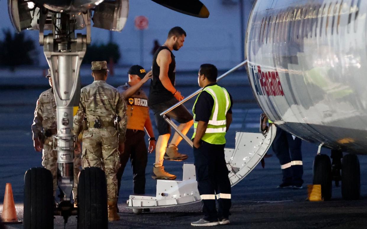 One of 29 men being deported to Colombia boards the plane at Panama City's international airport on Tuesday