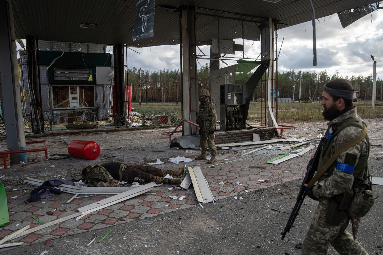 Ukrainian servicemen find a body of their comrade on the destroyed petrol station in the recently recaptured town of Lyman, Ukraine, Monday, Oct. 3, 2022.