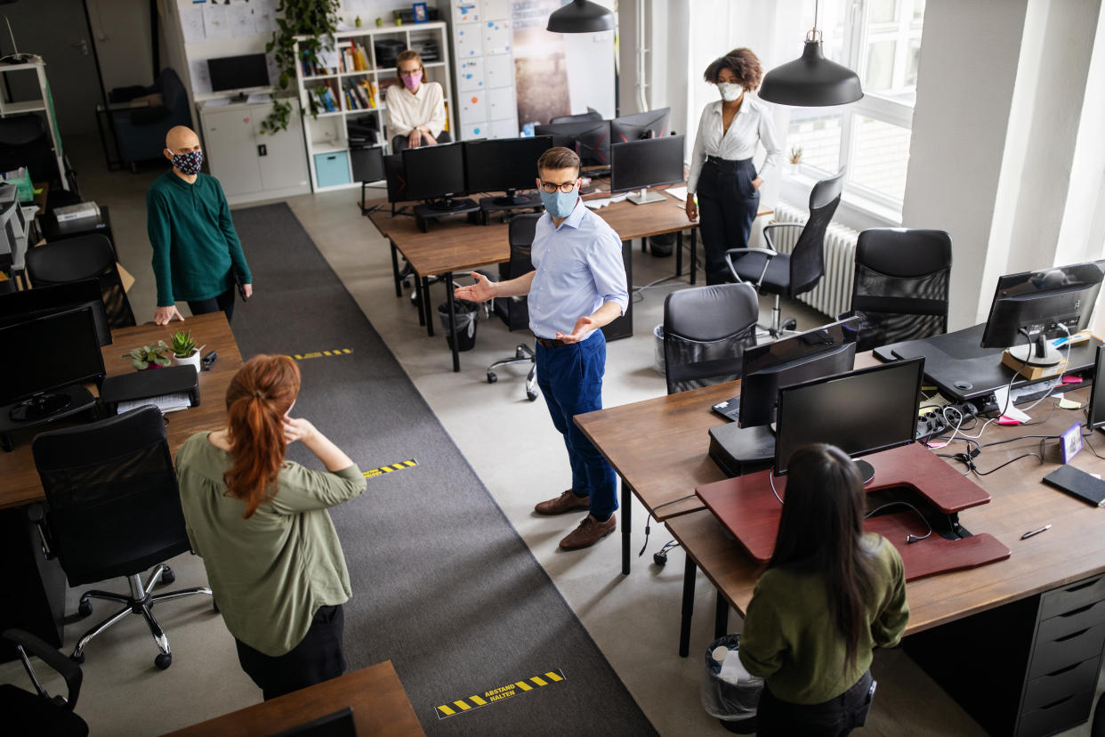 Office staff respecting social distancing during a meeting. Group of business men and women having a meeting in office during corona virus pandemic.