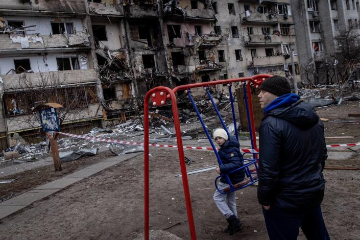 A boy plays on a swing in front of a damaged residential block hit by an early-morning missile strike in Kyiv on Feb. 25, 2022.