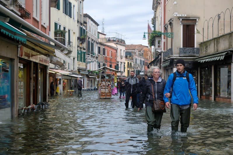 People walk in the flooded street during a period of seasonal high water in Venice