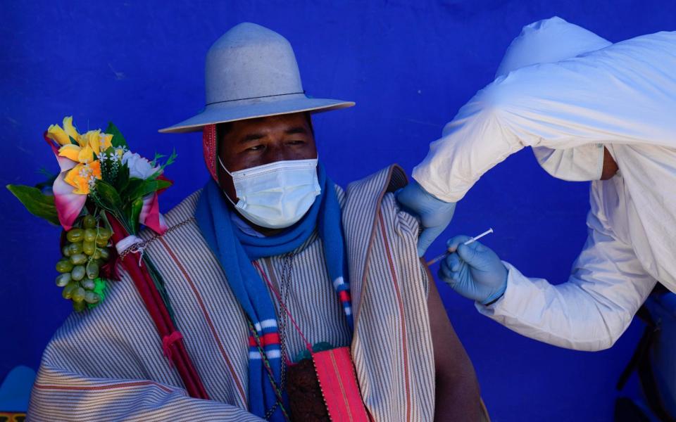 A resident is inoculated with a dose of the Sinopharm Covid-19 vaccine during a vaccination campaign targeting the Uru Chipaya Indigenous community - AP Photo/Juan Karita