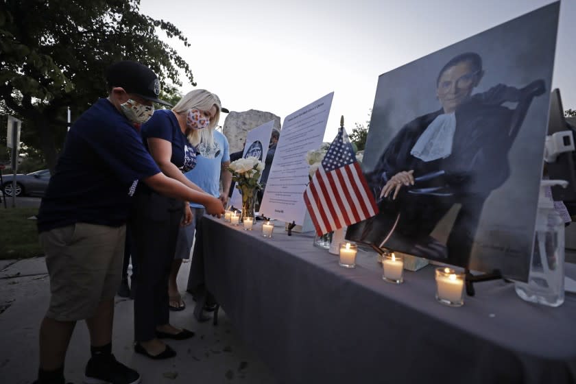 SAN PEDRO, CA - SEPTEMBER 21: Shannon Ross, president of the San Pedro Democratic Club and organizer of the candlelight vigil, lights a candle with her son Luke, 12, at the end of a vigil for Ruth Bader Ginsburg at the Port of Los Angeles Liberty Hill Plaza on Monday, Sept. 21, 2020 in San Pedro, CA. (Myung J. Chun / Los Angeles Times)