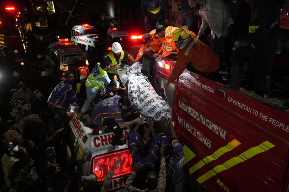 Firefighters and rescue workers recover a body from a burnt multi-story commercial building in Karachi, Pakistan, Wednesday, Dec. 6, 2023. A massive fire broke out Wednesday in a multi-story commercial building in Pakistan's largest southern port city of Karachi, killing a number of people and damaging several shops, police and rescue officials said. (AP Photo/Fareed Khan)