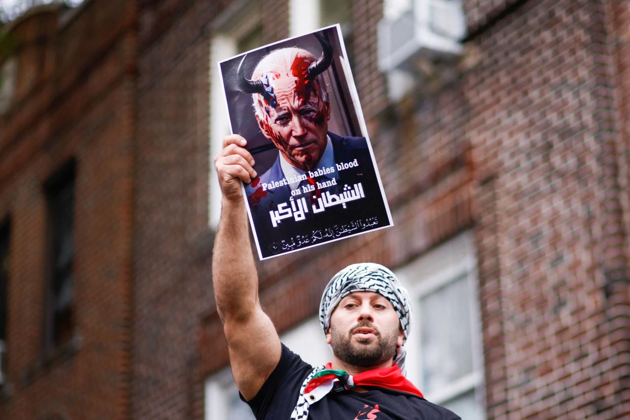 A man holds a sign depicting President Joe Biden as the devil as people rally in support of Palestinians in Brooklyn, New York, on Oct. 21, 2023.