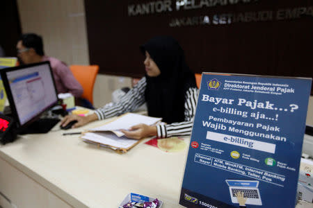 An employee at a government tax office sits behind a desk in Jakarta Indonesia February 23, 2017. REUTERS/Fatima Elkarim