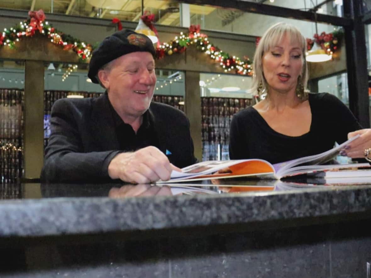 Chris Edwards, left, and Elaine Weeks, right, look at their latest book in Walkerville Brewery.  (Jennifer La Grassa/CBC - image credit)