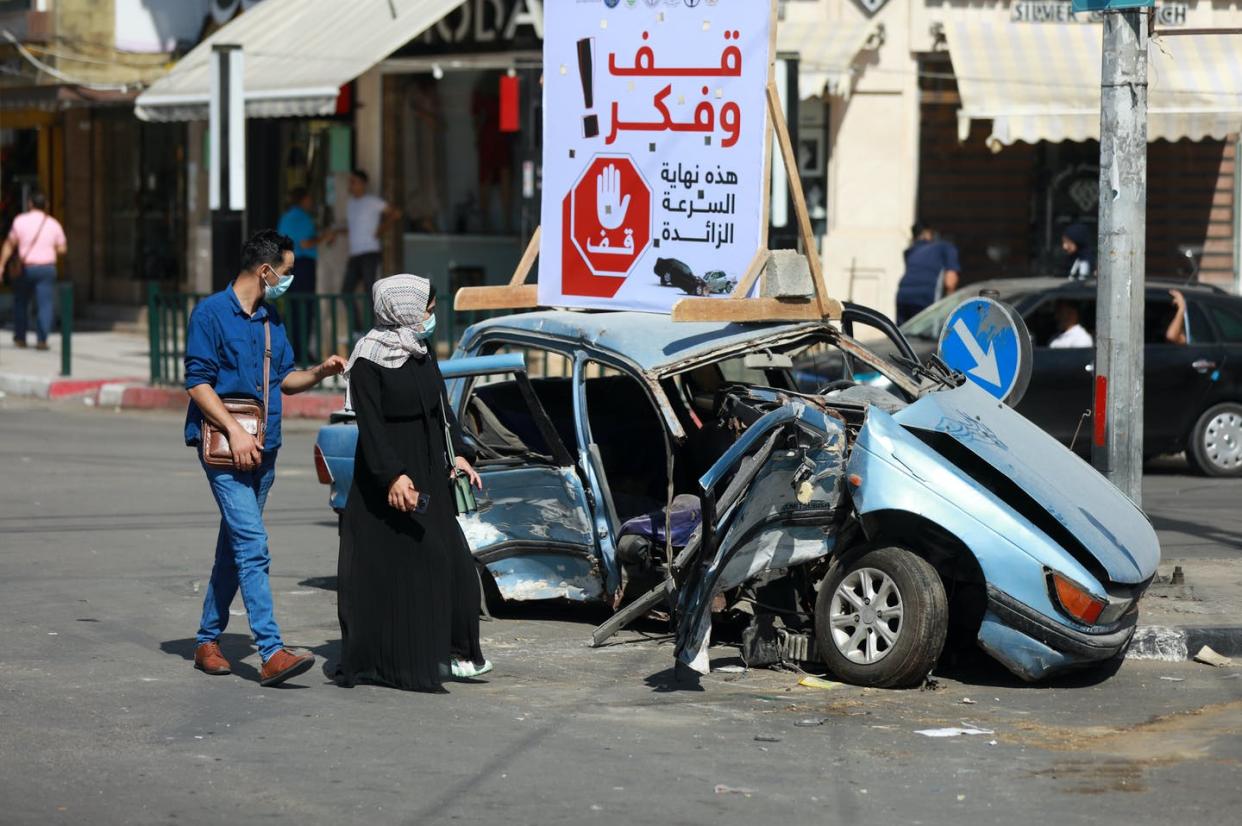 <span class="caption">Pedestrians pass the aftermath of a crash in Gaza City in the Gaza Strip on Oct. 11, 2021.</span> <span class="attribution"><a class="link " href="https://www.gettyimages.com/detail/news-photo/palestinians-walk-next-to-a-car-that-was-involved-in-a-news-photo/1235821622" rel="nofollow noopener" target="_blank" data-ylk="slk:Majdi Fathi/NurPhoto via Getty Images;elm:context_link;itc:0;sec:content-canvas">Majdi Fathi/NurPhoto via Getty Images</a></span>