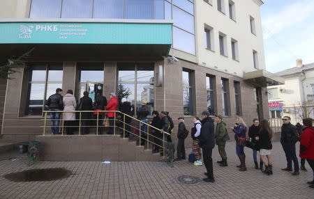 People stand in a line to use an ATM machine at a bank office in Simferopol, Crimea, November 26, 2015. REUTERS/Pavel Rebrov