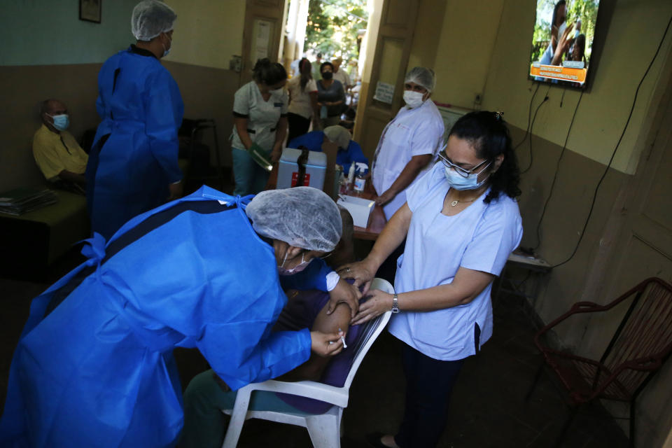 A nurse administers an AstraZeneca COVID-19 vaccine to an elderly patient at "Santo Domingo" senior home Asuncion, Paraguay, Saturday, April 10, 2021.(AP Photo/Jorge Saenz)