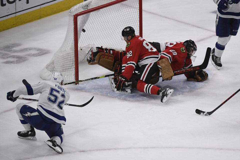 Tampa Bay Lightning defenseman Cal Foote (52) scores a goal past Chicago Blackhawks defenseman Caleb Jones (82) and goaltender Marc-Andre Fleury (29) during the second period of an NHL hockey game, Sunday, March 6, 2022, in Chicago. (AP Photo/Matt Marton)