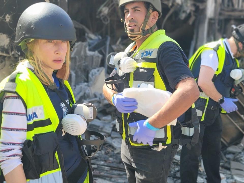 Valerie Dyksztejn wearing a yellow emergency response vest and helmet at the scene of destruction in Israel