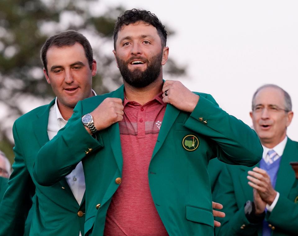 Scottie Scheffler (left) helps Jon Rahm into his green jacket after Rahm's Masters win.