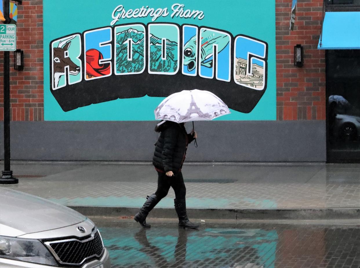 File photo - Ilena Shortt of Redding holds an umbrella as she walks to her car in the rain along Market Street on Wednesday, Dec. 15, 2021.