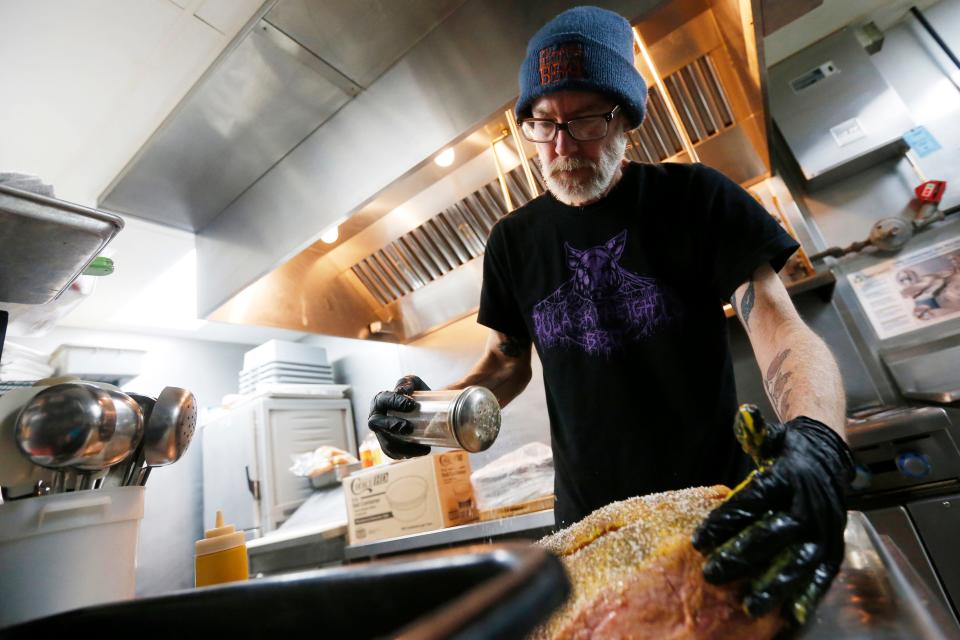 FILE - Chuck Ramsey, owner of Pulaski Heights BBQ, prepares a brisket before putting it on the smoker in Athens, Ga., on Monday, June 21, 2021.