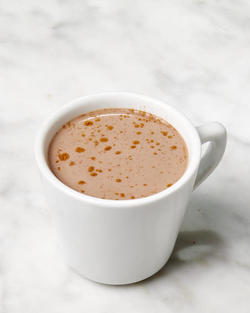 Angled shot of Nigella Lawson's hot chocolate recipe in a white mug, topped with cinnamon.