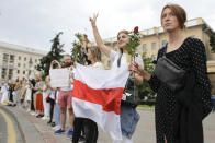 Belarusian opposition supporters hold flowers and flash victory signs during a protest in Victory Square in Minsk, Belarus, Thursday, Aug. 20, 2020. Demonstrators are taking to the streets of the Belarusian capital and other cities, keeping up their push for the resignation of the nation's authoritarian leader. President Alexander Lukashenko has extended his 26-year rule in a vote the opposition saw as rigged. (AP Photo/Sergei Grits)