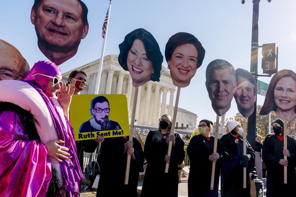 An abortion rights advocate in costume stands in front of Supreme Court justice posters as people demonstrate in front of the U.S. Supreme Court, Wednesday, Dec. 1, 2021, in Washington, as the court hears arguments in a case from Mississippi, where a 2018 law would ban abortions after 15 weeks of pregnancy, well before viability.