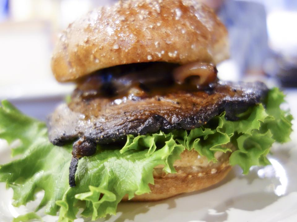 The Shroom features a marinated portabella mushroom on a toasted wheat bun with provolone, garlic aioli and honey balsamic grilled onions.