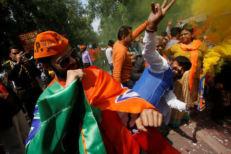Supporters of Bharatiya Janata Party (BJP) celebrate after learning of the initial poll results outside the party headquarters in New Delhi, March 11, 2017. REUTERS/Adnan Abidi