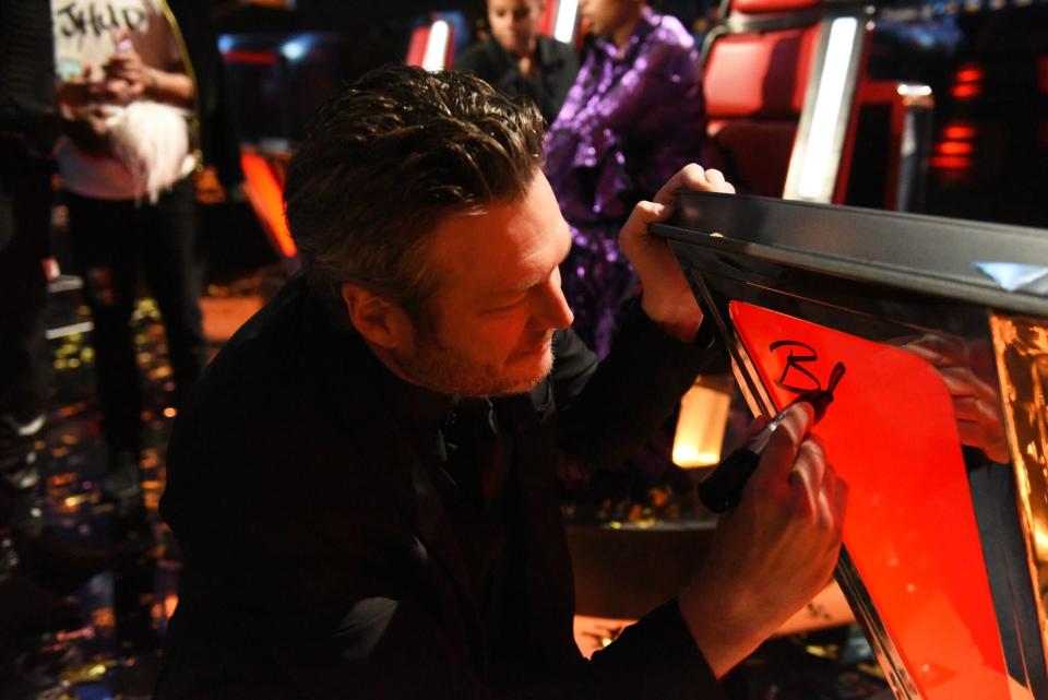 Blake Shelton autographs a classic <em>Voice</em> chair. (Photo: NBC)