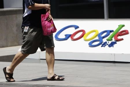 An employee walks past the logo of Google in front of its former headquarters, in Beijing June 2, 2011. REUTERS/Jason Lee/Files