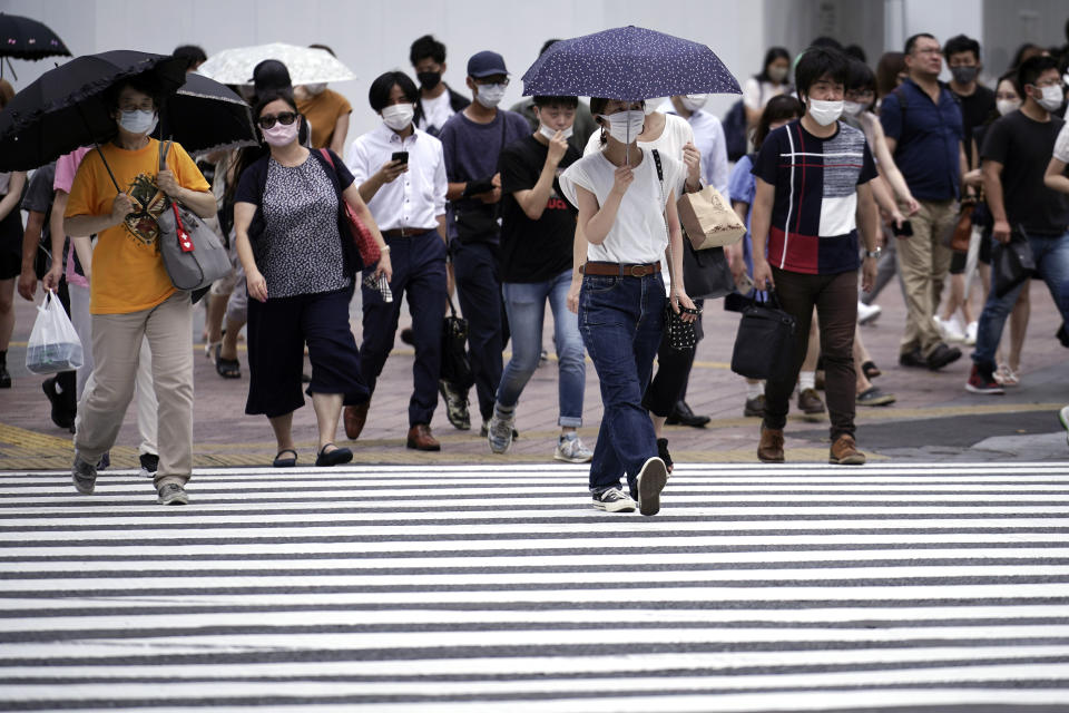 People wearing face masks to help curb the spread of the coronavirus walk at a Shibuya pedestrian crossing Thursday, Aug. 13, 2020, in Tokyo. The Japanese capital confirmed more than 200 coronavirus cases on Thursday. (AP Photo/Eugene Hoshiko)
