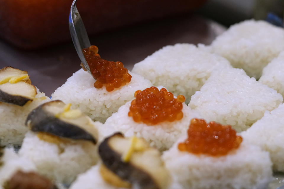 Ikura, or salmon roes, are added to onigiri, rice ball, at a Taro Tokyo Onigiri shop in Tokyo, on June 5, 2024. The word "onigiri" just became part of the Oxford English Dictionary this year. The humble sticky-rice ball, a mainstay of Japanese food, has entered the global lexicon. (AP Photo/Shuji Kajiyama)