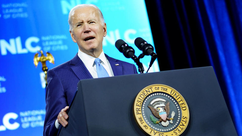 President Biden speaks at a podium marked with the presidential seal.