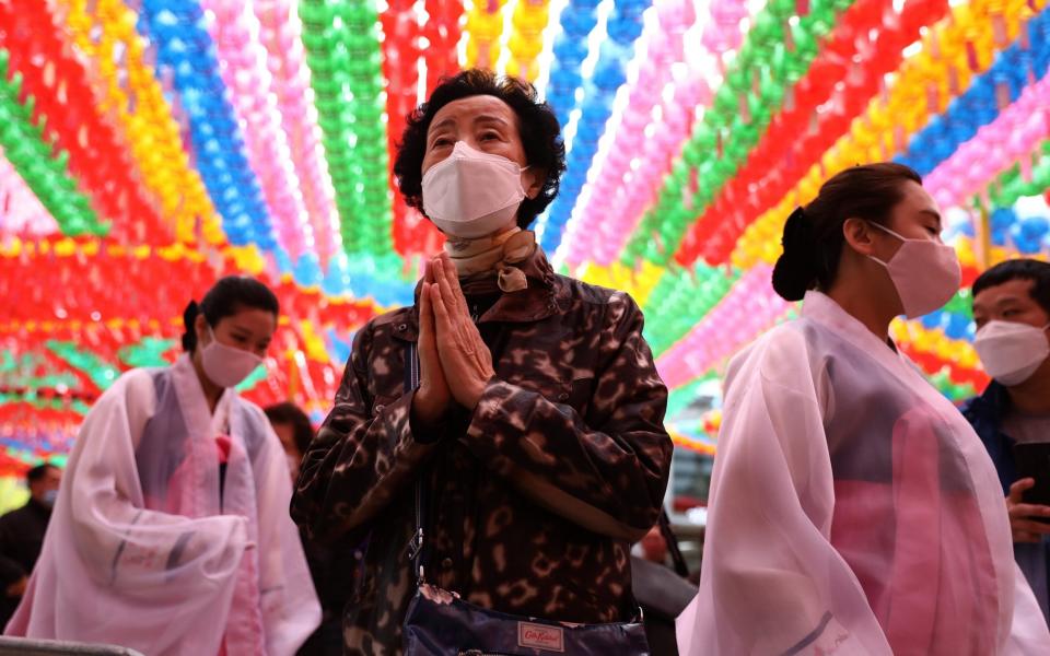 A buddhist believer wears a mask as a preventive measure against the coronavirus (COVID-19), as she pray during a birthday of Buddha and service to pray for overcoming the coronavirus (COVID-19) pandemic at Jogyesa Temple on April 30, 2020 in Seoul, South Korea - Chung Sung-Jun