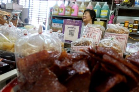 An advertisement board displaying a QR code is seen as a vendor waits for customers at a market in Bangkok, Thailand, November 22, 2017. Picture taken November 22, 2017. REUTERS/Athit Perawongmetha