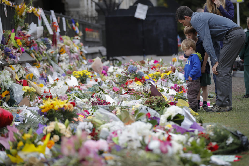 Mourners lay flowers on a wall at the Botanical Gardens in Christchurch, paying tribute at a makeshift memorial to the 50 people slain by a gunman at two mosques. Source: AP Photo/Vincent Thian