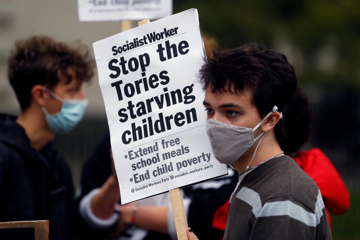 A boy holds a banner during a protest demanding free school meals for children in England (REUTERS)